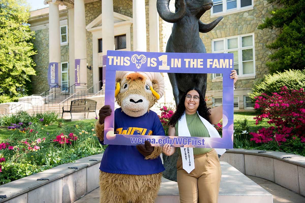 large, student standing with Rammy in front of the ram statue
