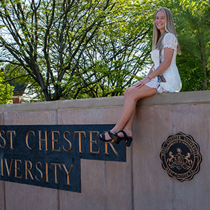 thumbnail, student sitting on wall, sign West Chester University