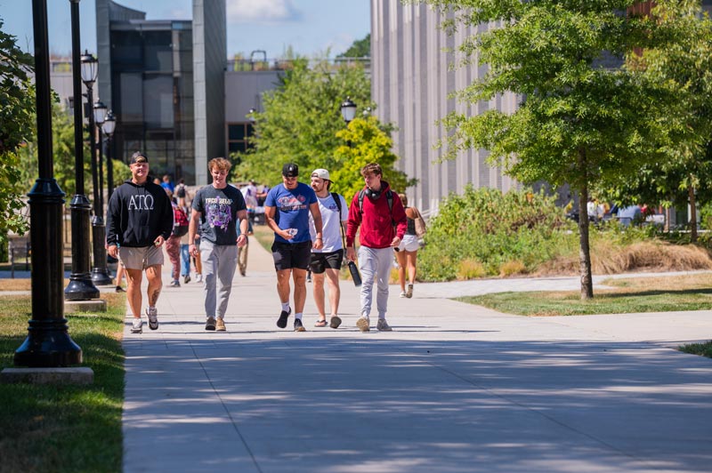 A group of boys walking through campus with SECC in the background