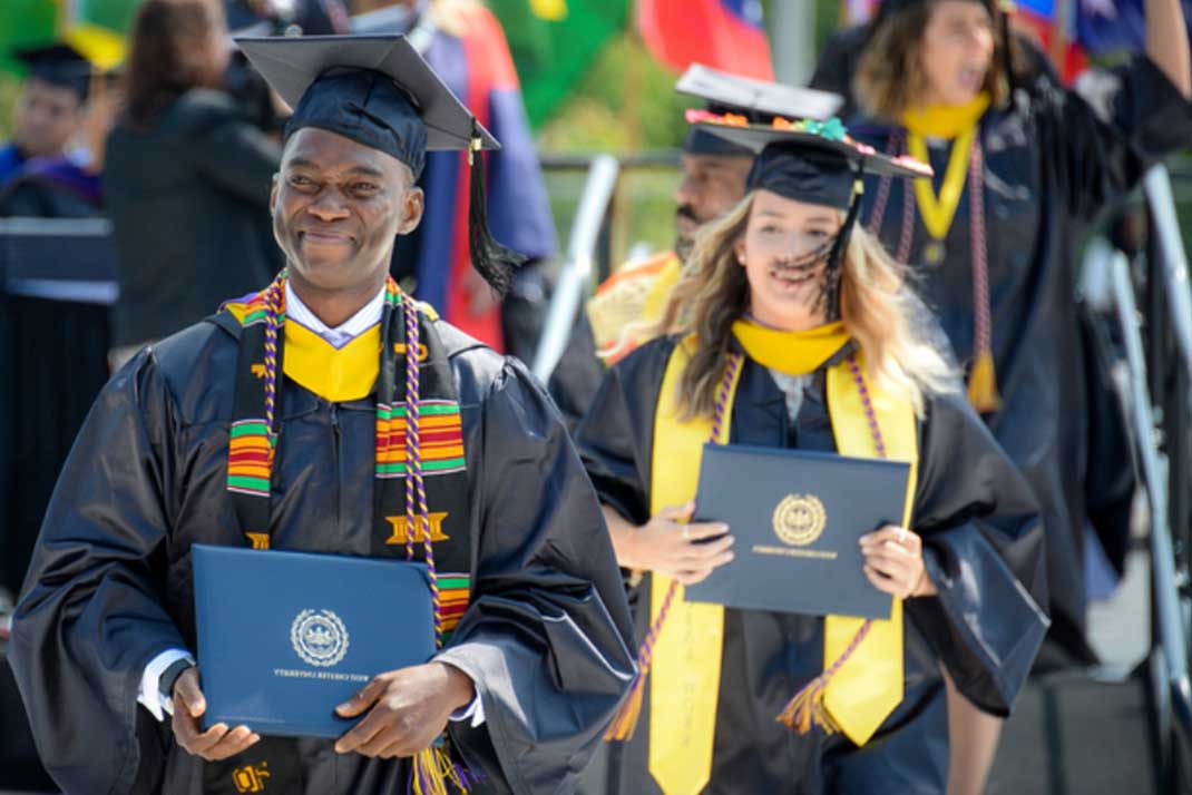 Male student and female student walking at graduation.