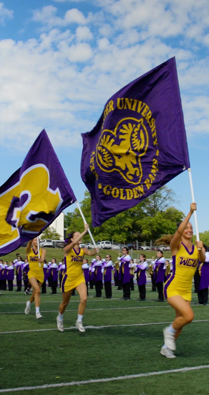 Cheerleaders running with flags at football game