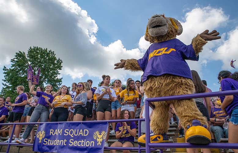 Rammy standing in the bleachers in front of the Ram Squad Student Section