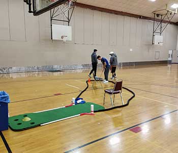 Students golfing indoors