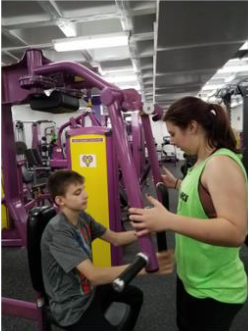 younger person working out at gym with trainer