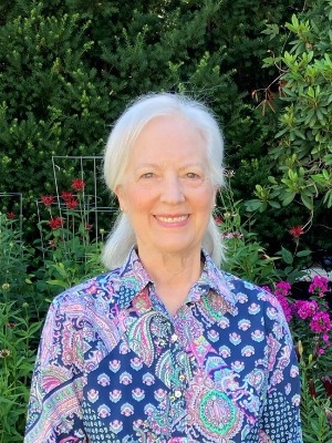 Photo of Dr. Janet Lacey in a bright blue floral shirt in a garden