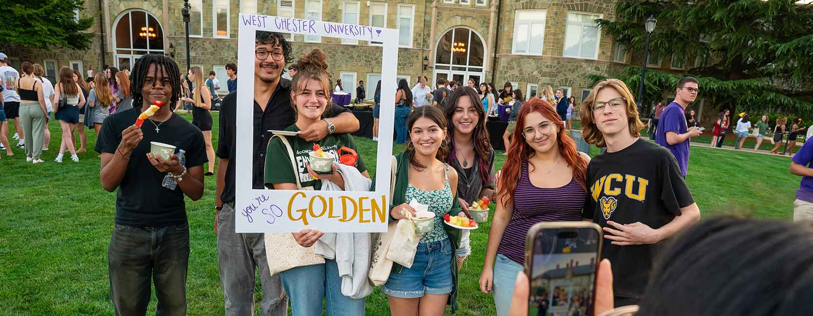 Students at campus event holding a giant polaroid picture frame