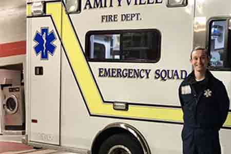 Student standing in front of an ambulance. Follow for student success story.