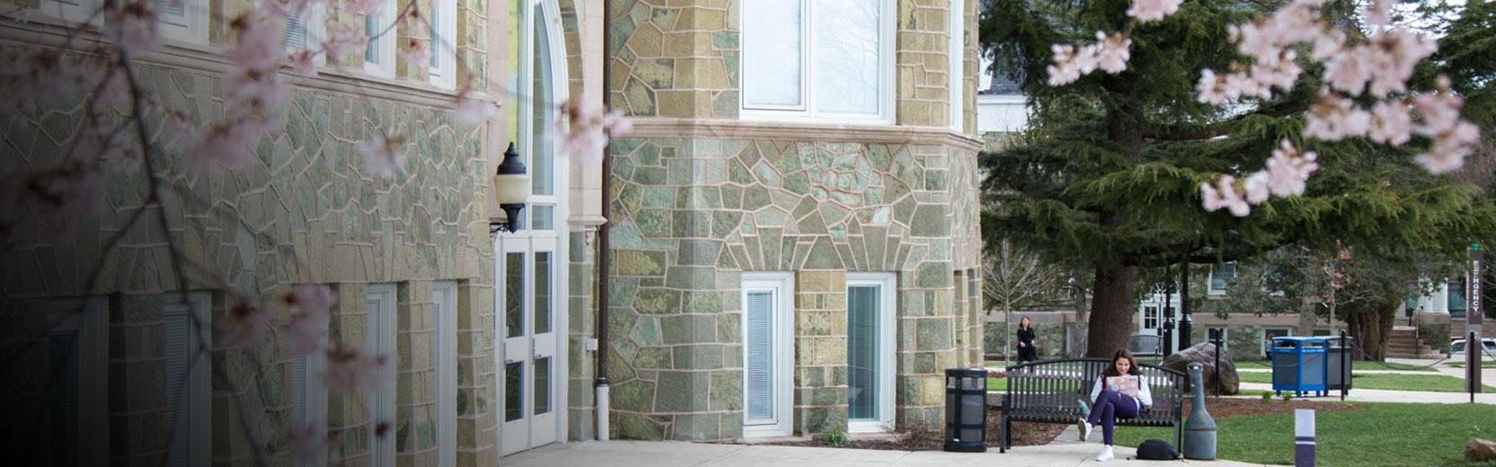 Old brick building with a woman sitting on a bench.