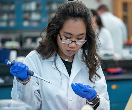 student working with a syringe in a lab