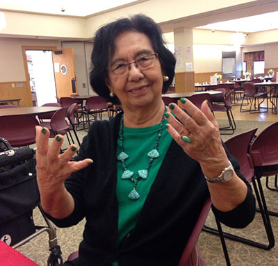 elderly woman showing holding up her hands showing her polished fingernails