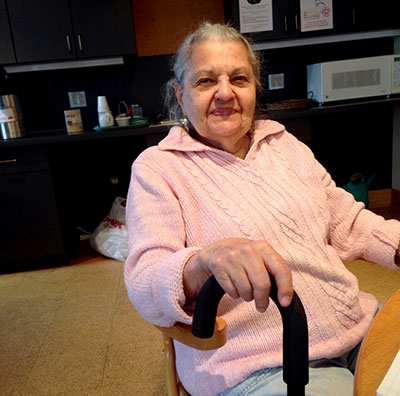 elderly woman sitting in a chair holding a cane