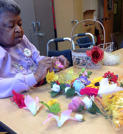 elderly woman decorating a basket with silk flowers
