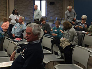 elderly people sitting in chairs in rows