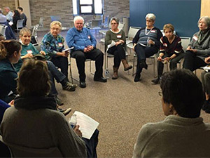 elderly people sitting in chairs in a circle