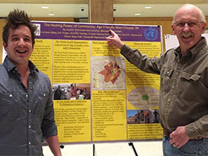 male student with male professor standing in front of a poster