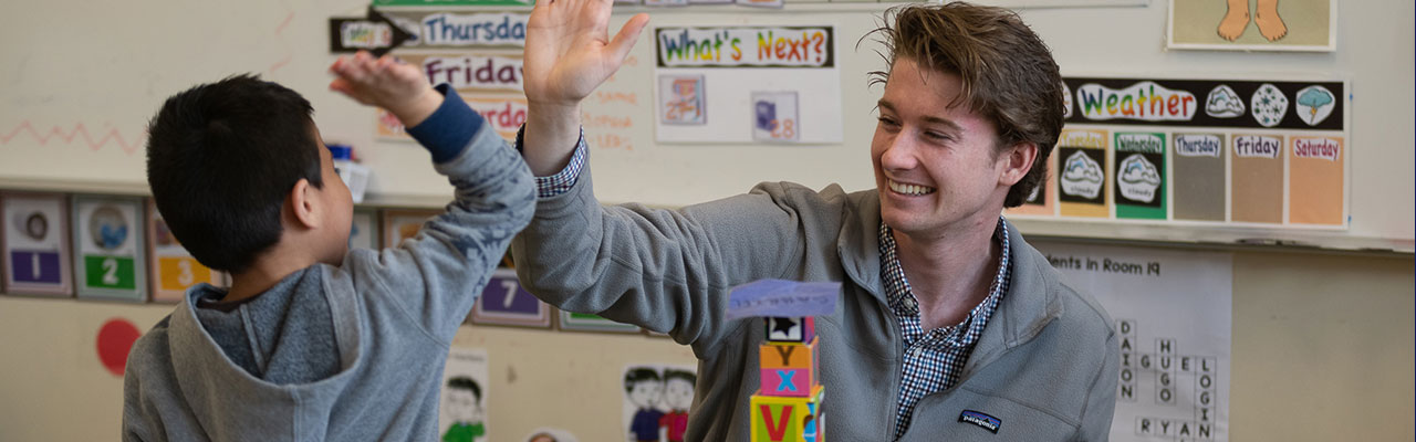 College student and child high-fiving in a classroom