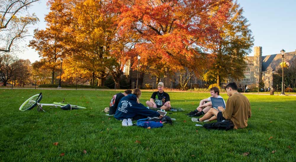 A group of students sitting in the grass in the academic quad on wcu campus