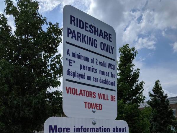 Two rideshare parking spots with a white car parked in front